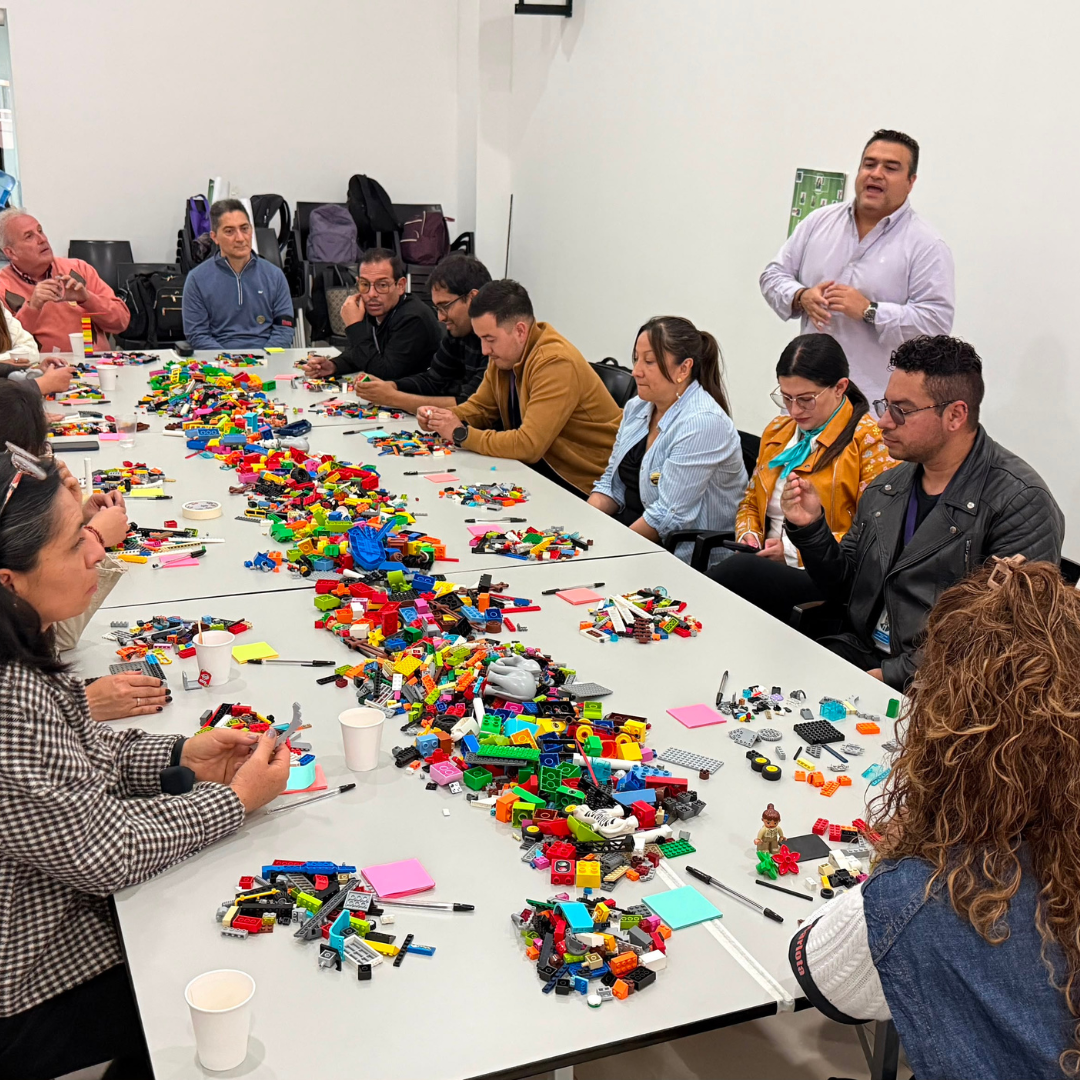Equipo construyendo modelos alrededor de una mesa con piezas LEGO®